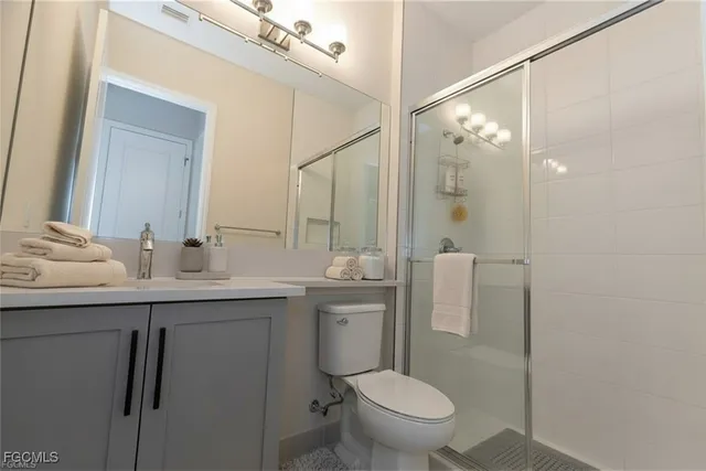 a view of an empty room with wooden floor and a kitchen
