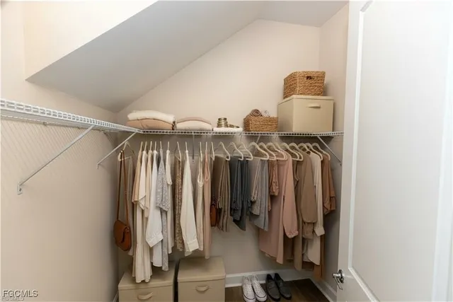 a view of an empty room with wooden floor kitchen and a window
