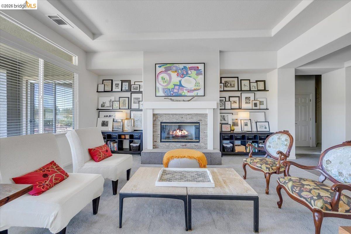 258 Rock Ridge Lane Copperopolis, CA 95228 - Photo 22 of 47 Living room featuring a glass covered fireplace, carpet flooring, and a tray ceiling