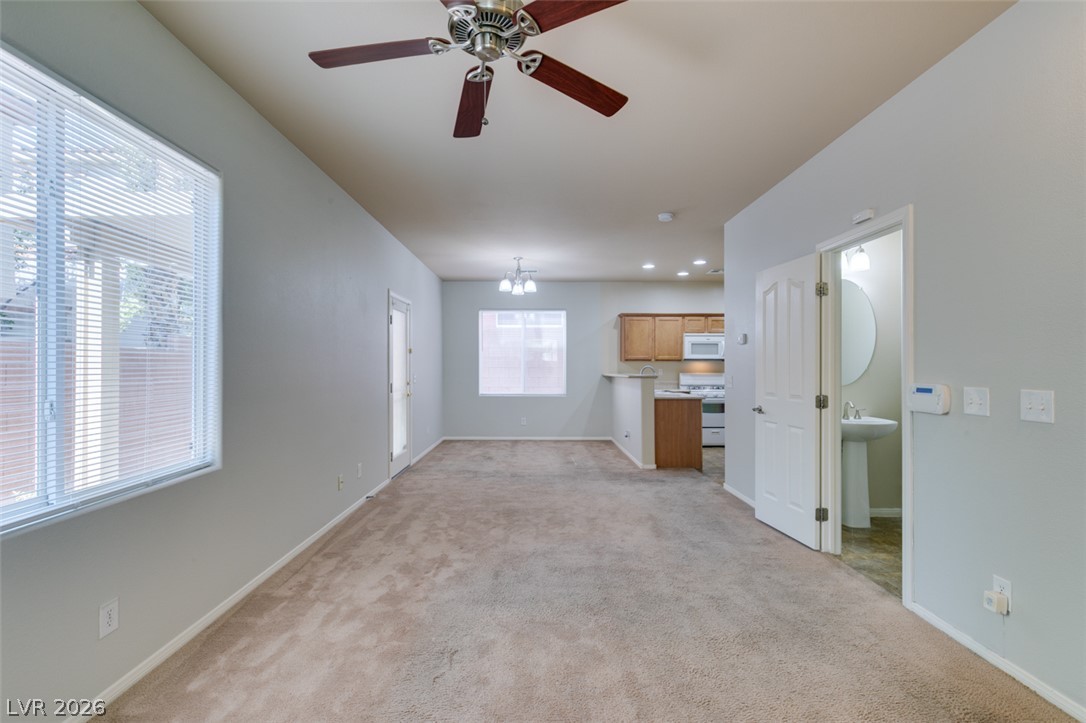 8937 Caledon Ridge Court Las Vegas, NV 89149 - Photo 11 of 43 A well-lit main living space offers a comfortable carpeted area connecting to a functional kitchen.