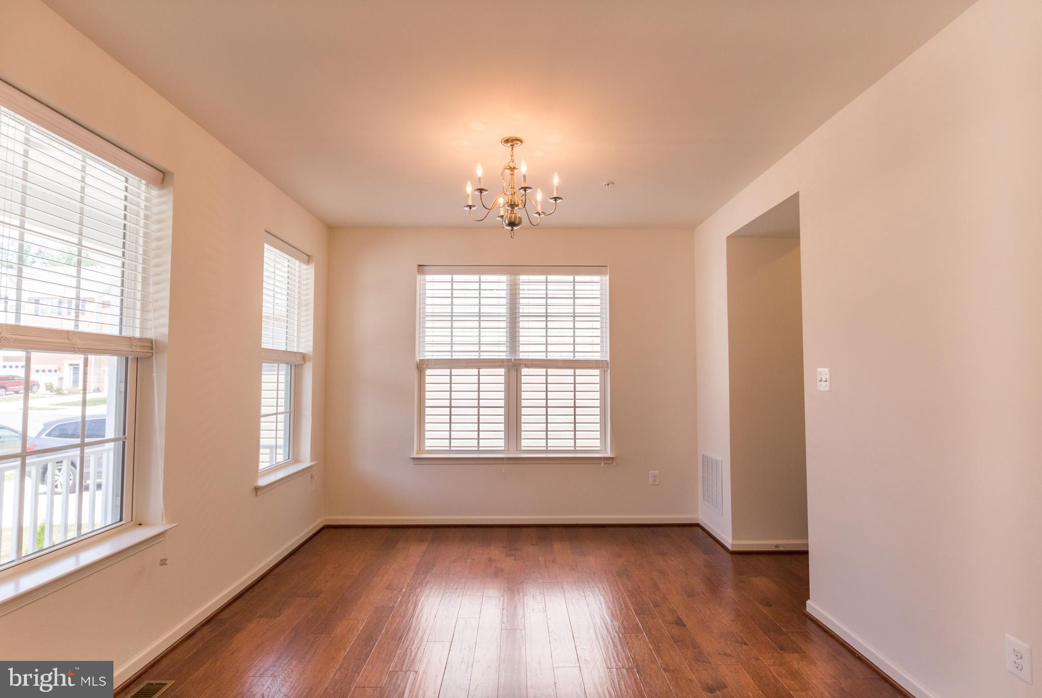 902 Ramble Run Road Middle River, MD 21220 - Photo 15 of 30 an empty room with wooden floor chandelier and windows