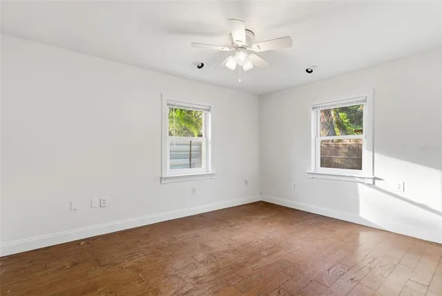 an empty room with windows and chandelier fan