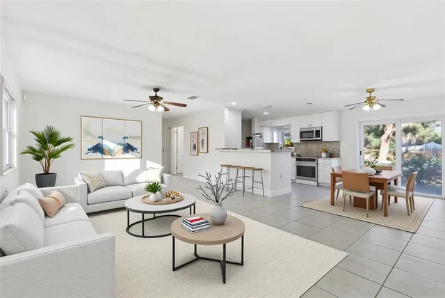 a living room with furniture potted plant and kitchen view