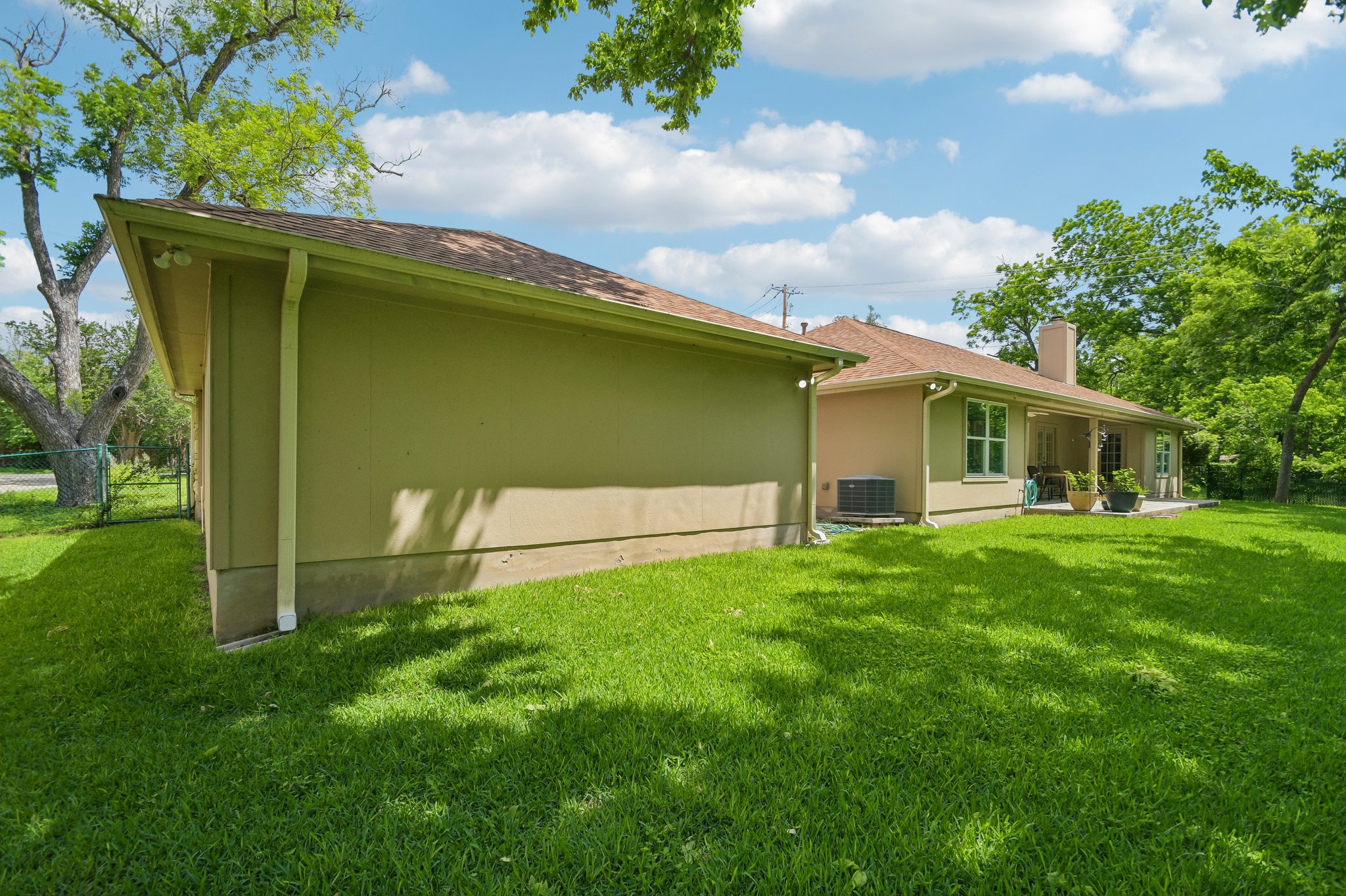 307 West 4th Street Elgin, TX 78621 - Photo 36 of 40 Expansive green lawn surrounds the property, featuring a stucco exterior and a covered patio