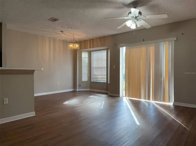 a view of a livingroom with a chandelier fan and windows