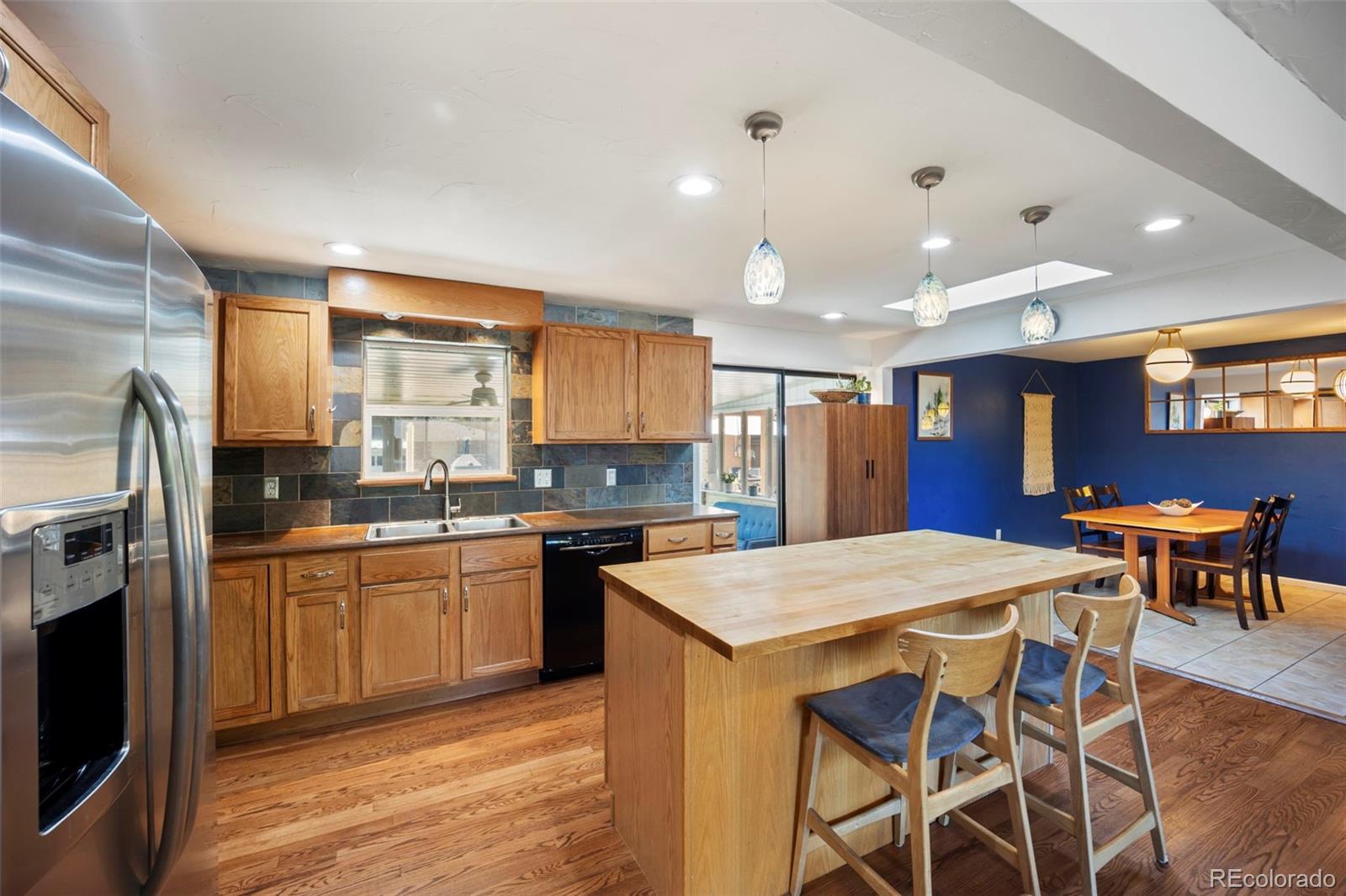 2605 Reed Court Wheat Ridge, CO 80033 - Photo 13 of 49 a kitchen with stainless steel appliances granite countertop a table chairs sink refrigerator and cabinets