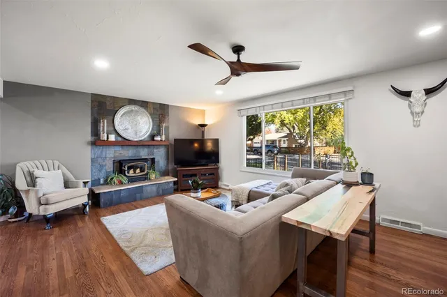 a living room with furniture a fireplace flat screen tv and a large window