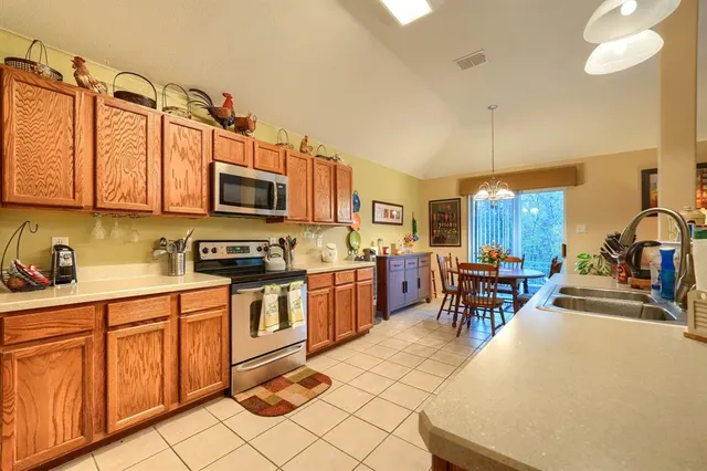 a kitchen with stainless steel appliances a stove a sink a microwave and chairs