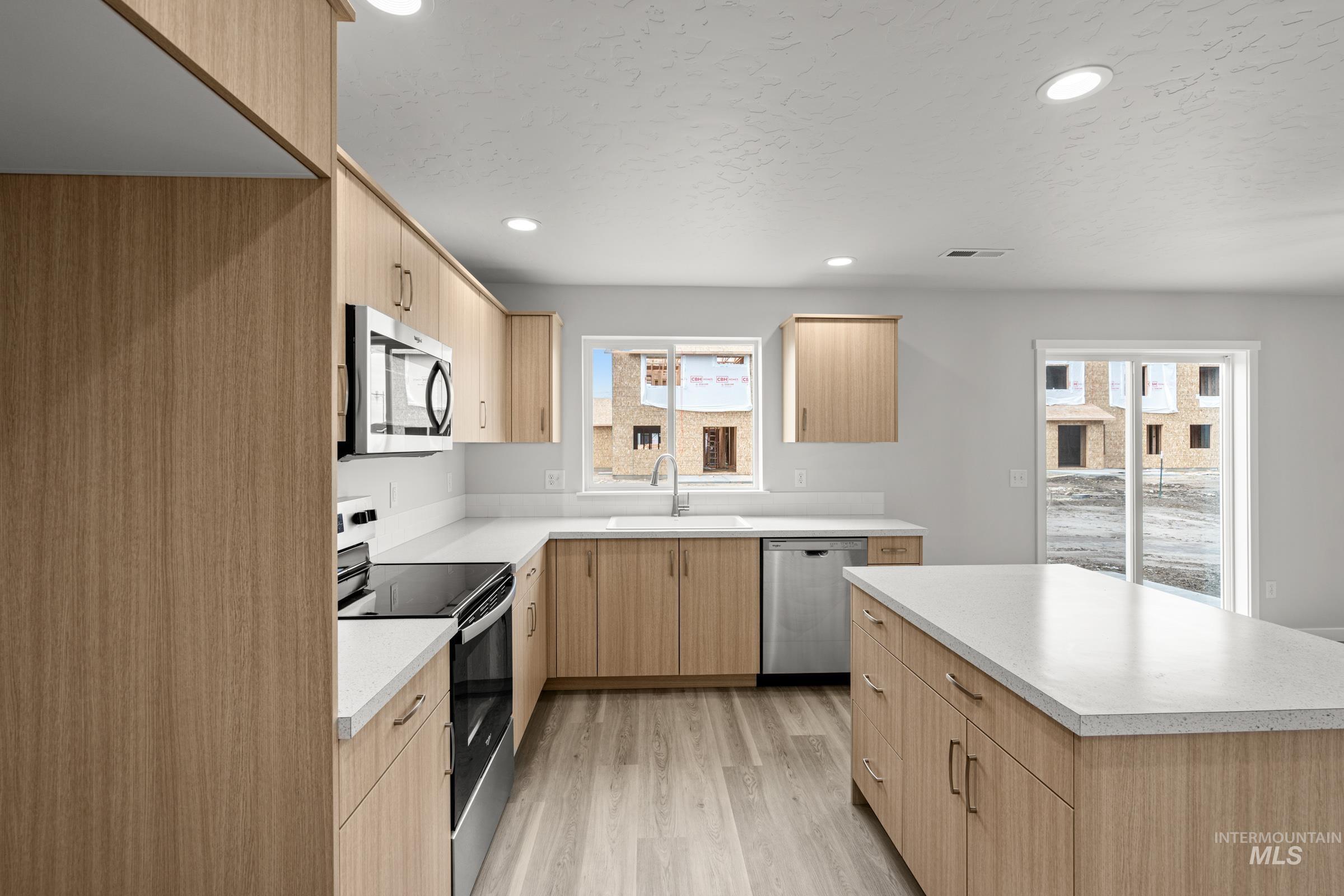 14056 Shiny Spruce Street Caldwell, ID 83607 - Photo 5 of 25 Modern kitchen featuring light wood-finish cabinetry, white countertops, and stainless steel appliances