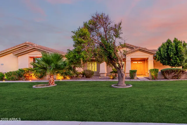 a front view of a house with garden and trees
