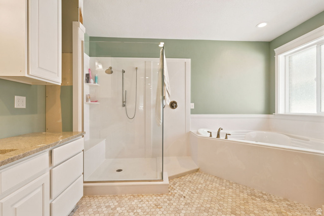 580 North 300 East Logan, UT 84321 - Photo 40 of 74 Bathroom featuring a built-in soaking tub, a glass-enclosed shower with a bench, and a vanity with a light-toned countertop