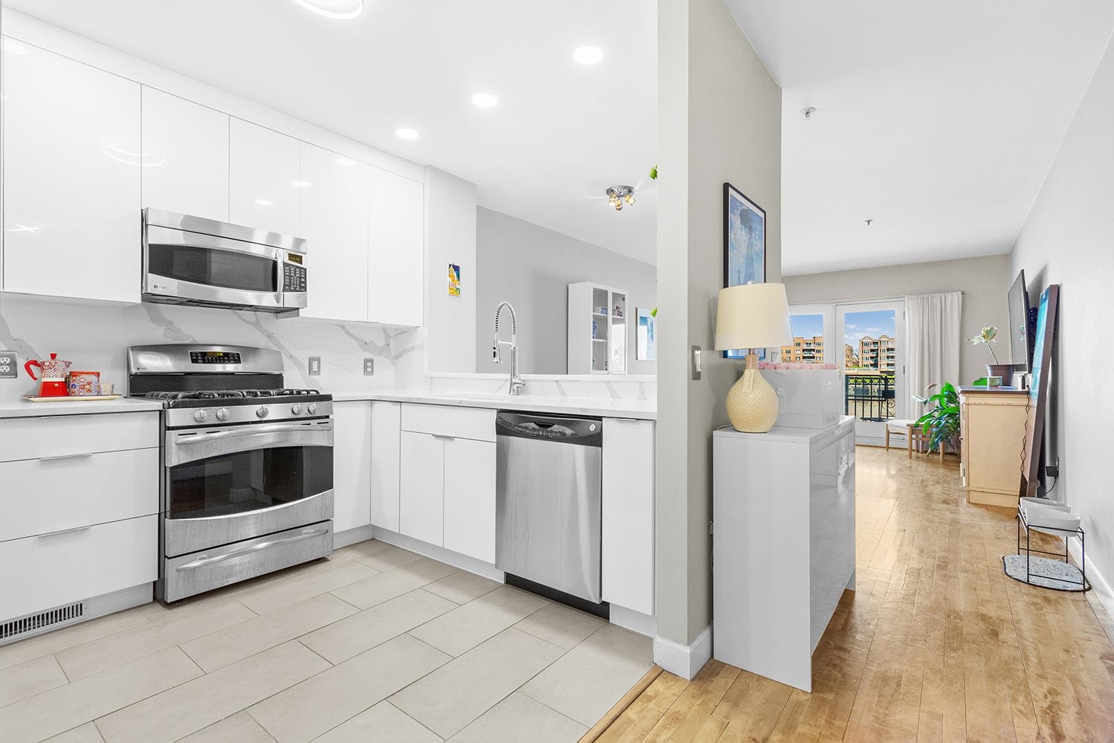 154 The Promenade, Unit 154 Edgewater, NJ 07020 - Photo 7 of 12 a kitchen with stainless steel appliances a stove a refrigerator a sink cabinets and wooden floor
