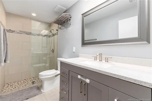 a bathroom with a granite countertop sink a toilet a mirror and shower