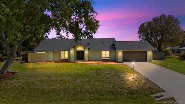 a front view of house with yard and trees in the background