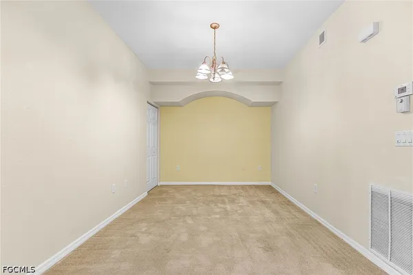 an empty room with a chandelier fan and wooden floor
