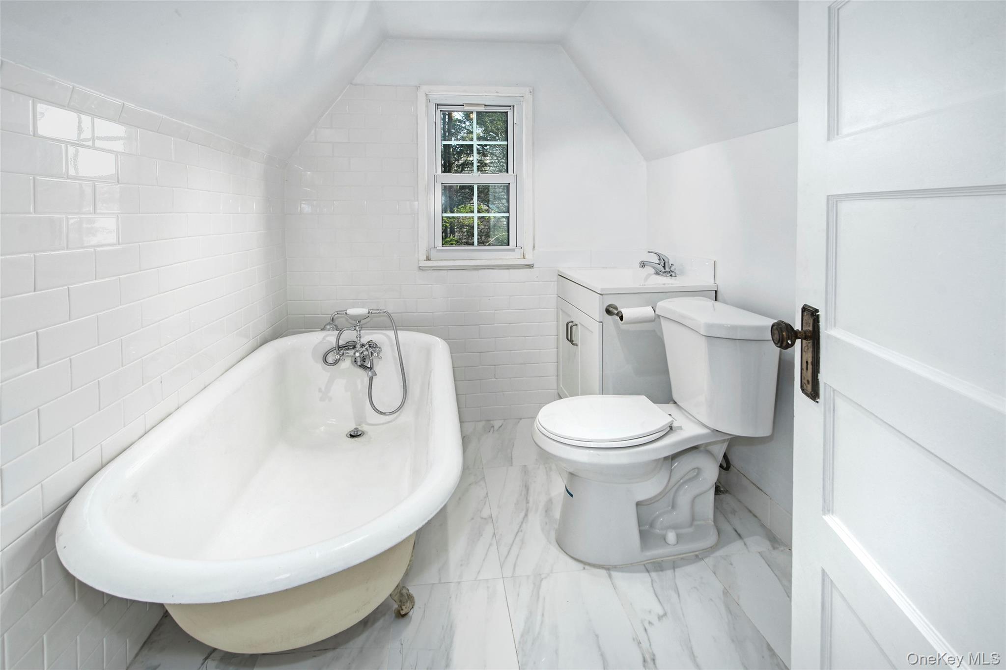 2 Byworth Road New Rochelle, NY 10804 - Photo 26 of 31 Bathroom featuring a freestanding bath, toilet, tile walls, marble finish floors, and vaulted ceiling