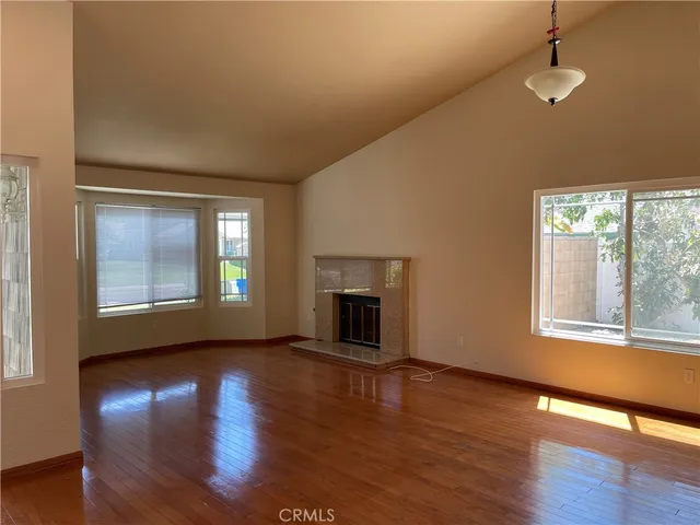 an empty room with wooden floor fireplace and windows
