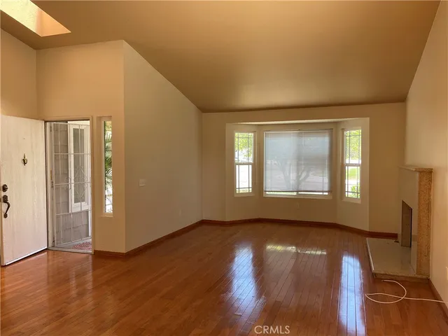 a view of an empty room with window and wooden floor