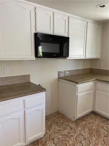 a kitchen with granite countertop white cabinets and stainless steel appliances