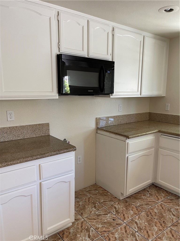 1341 Grovehill Drive Riverside, CA 92507 - Photo 5 of 23 a kitchen with granite countertop white cabinets and stainless steel appliances
