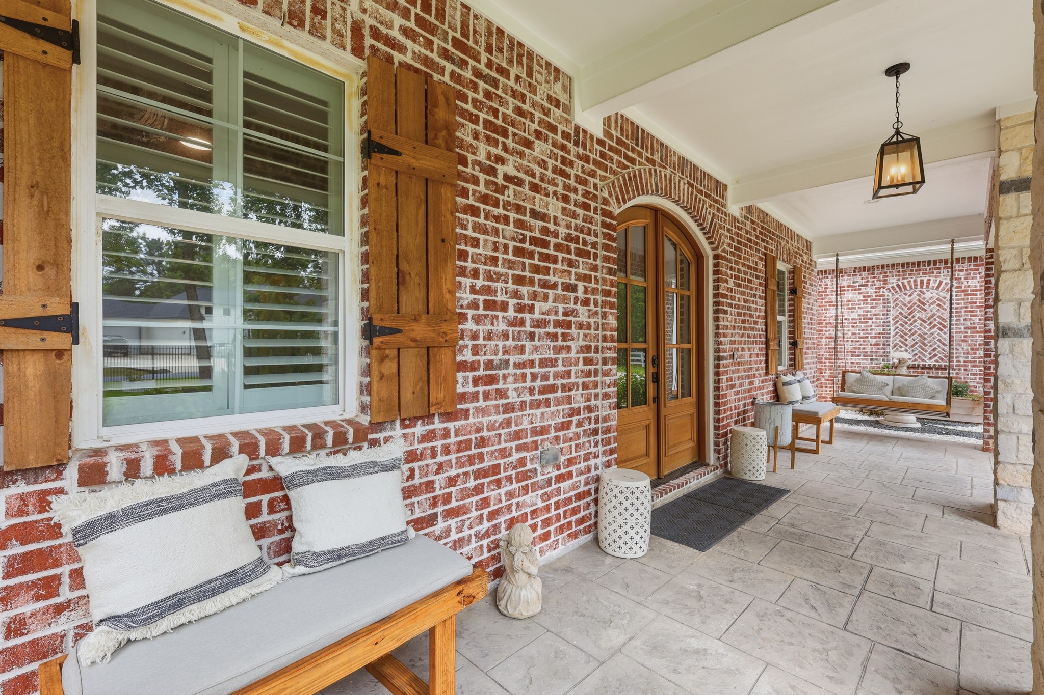 7106 Hampton Court Spring, TX 77389 - Photo 6 of 31 Front porch features wooden swings and benches on each side. The space features cozy seating, a stylish hanging bench, and elegant lighting, creating a warm and welcoming entrance.