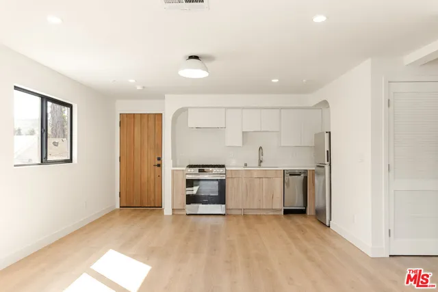 a view of a kitchen with a sink and dishwasher a refrigerator with wooden floor