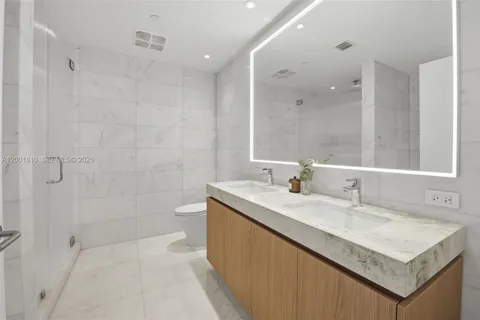 a bathroom with a sink a toilet a mirror and shower