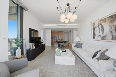 a living room with furniture a chandelier and a flat screen tv