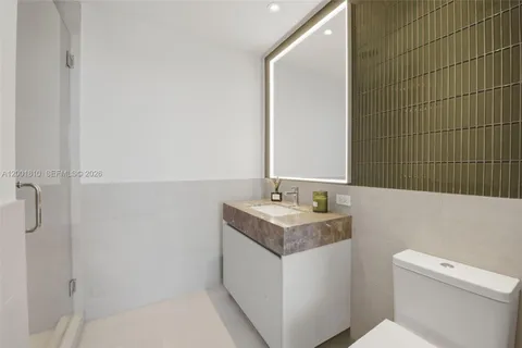 a bathroom with a granite countertop sink a toilet and a mirror