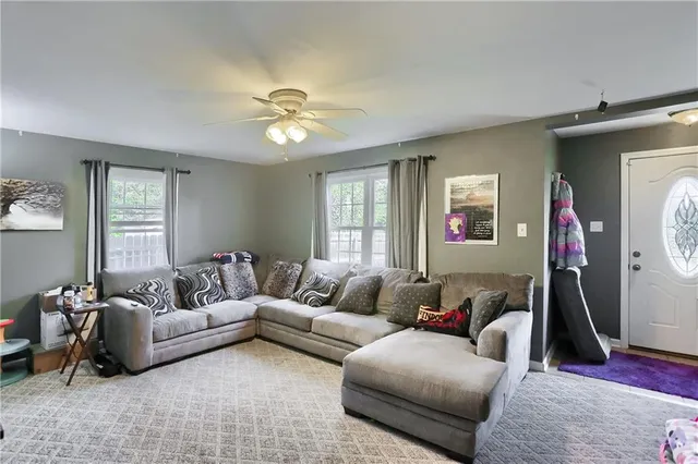 a living room with furniture a ceiling fan and a window