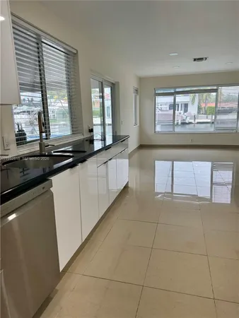 a large white kitchen with granite countertop a sink and white cabinets