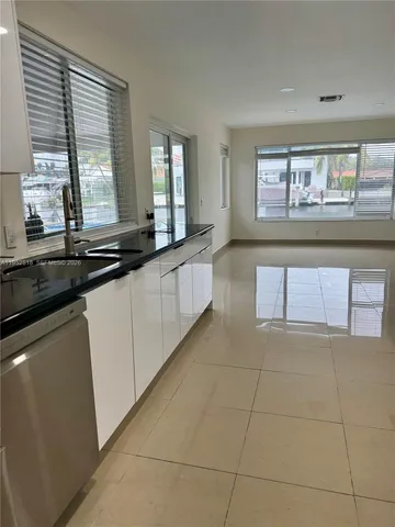 a large white kitchen with granite countertop a sink and white cabinets