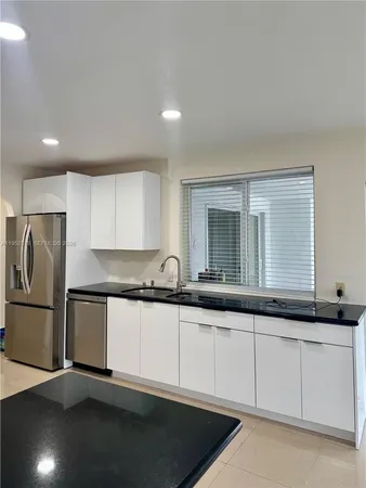 a kitchen with granite countertop white cabinets and a refrigerator