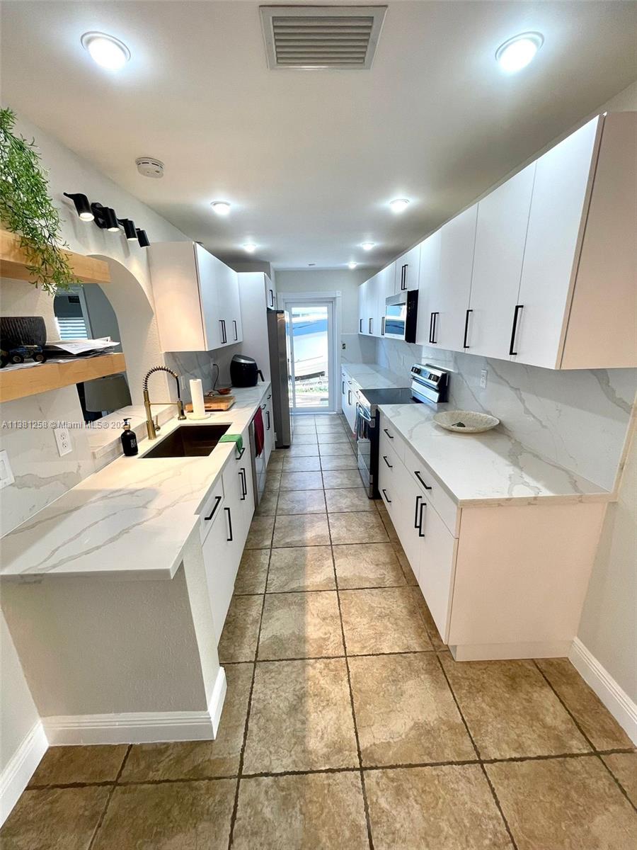 25305 Southwest 124th Court Homestead, FL 33032 - Photo 13 of 39 a large white kitchen with stainless steel appliances granite countertop a sink and cabinets