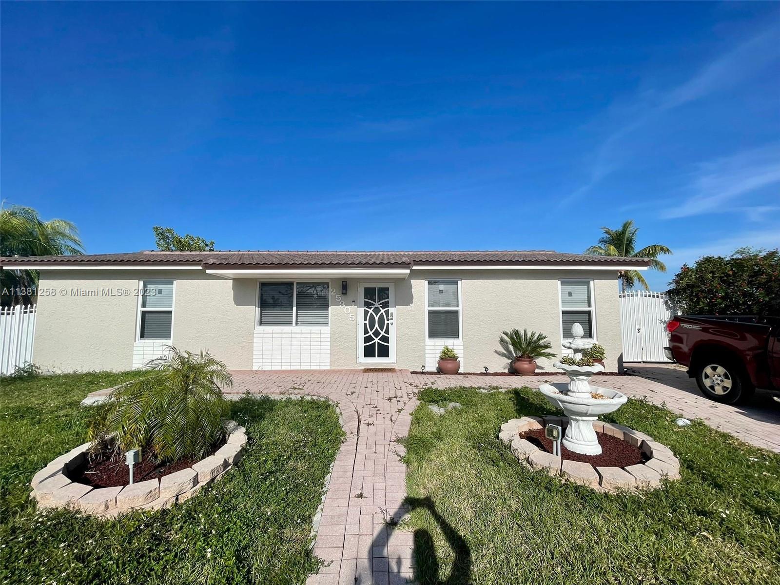 25305 Southwest 124th Court Homestead, FL 33032 - Photo 2 of 39 a front view of a house with a yard outdoor seating and garage