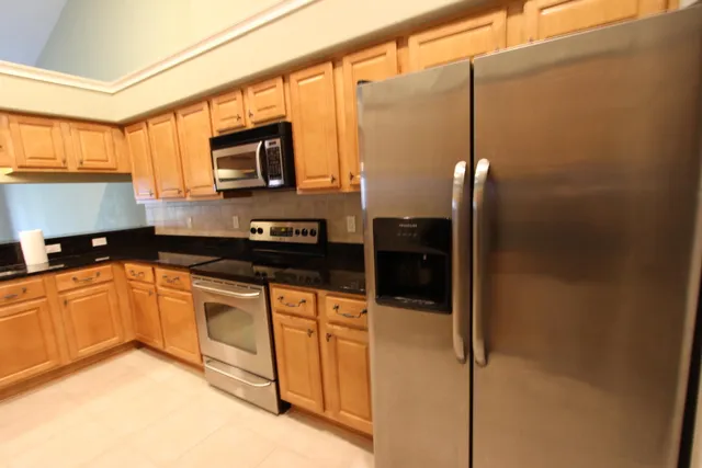 a kitchen with stainless steel appliances granite countertop a refrigerator a oven a sink with granite countertops and cabinets