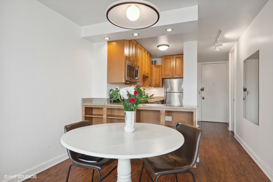 1 East Scott Street, Unit 2011 Chicago, IL 60610 - Photo 5 of 13 a kitchen with stainless steel appliances granite countertop a dining table chairs and a refrigerator