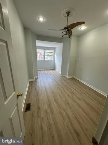 a view of a hallway with wooden floor and a ceiling fan