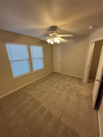 an empty room with windows and fan