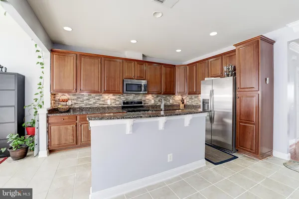 a kitchen with granite countertop a refrigerator stove top oven and sink