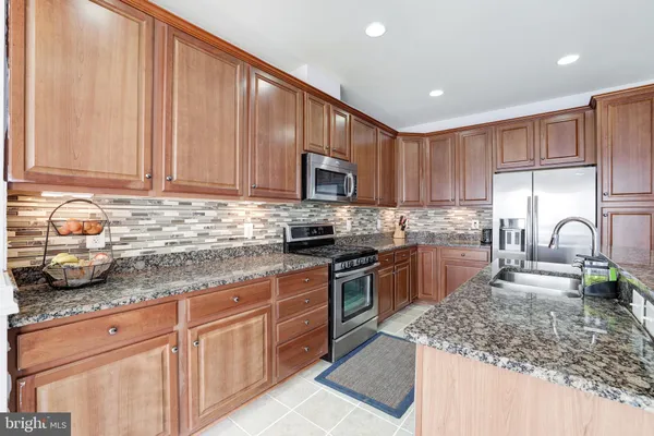 a kitchen with granite countertop a sink dishwasher stove and cabinets with wooden floor