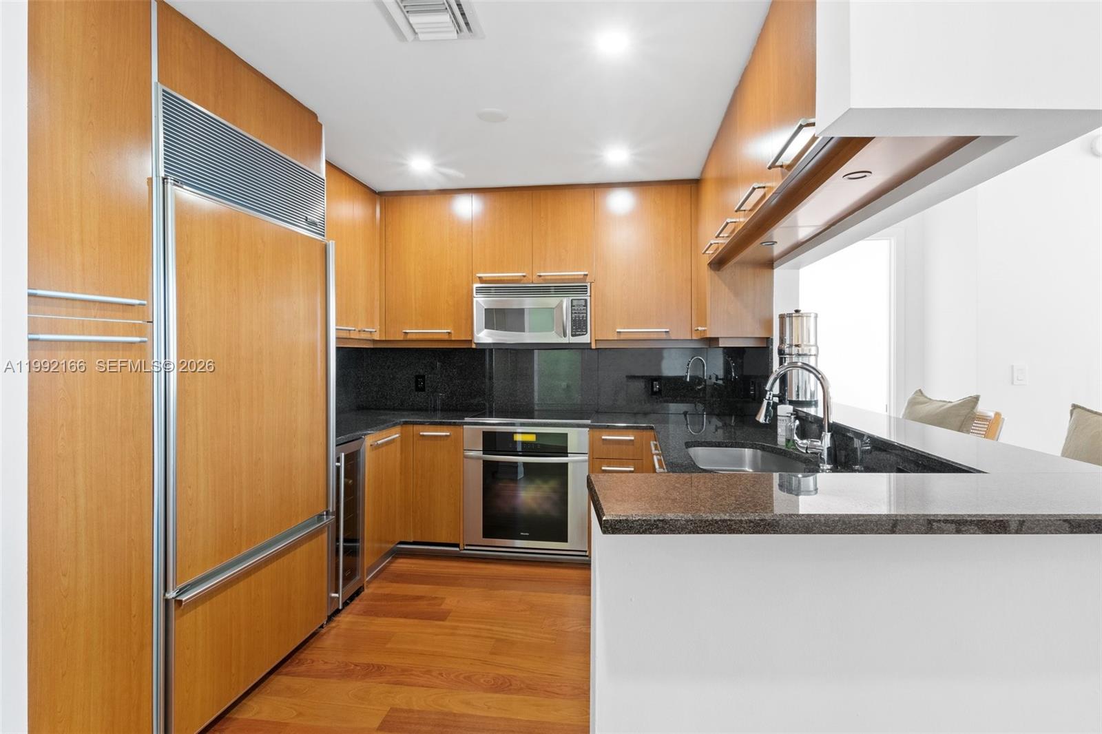 901 Brickell Key Boulevard, Unit 1609 Miami, FL 33131 - Photo 12 of 35 a kitchen with granite countertop a refrigerator stove and sink