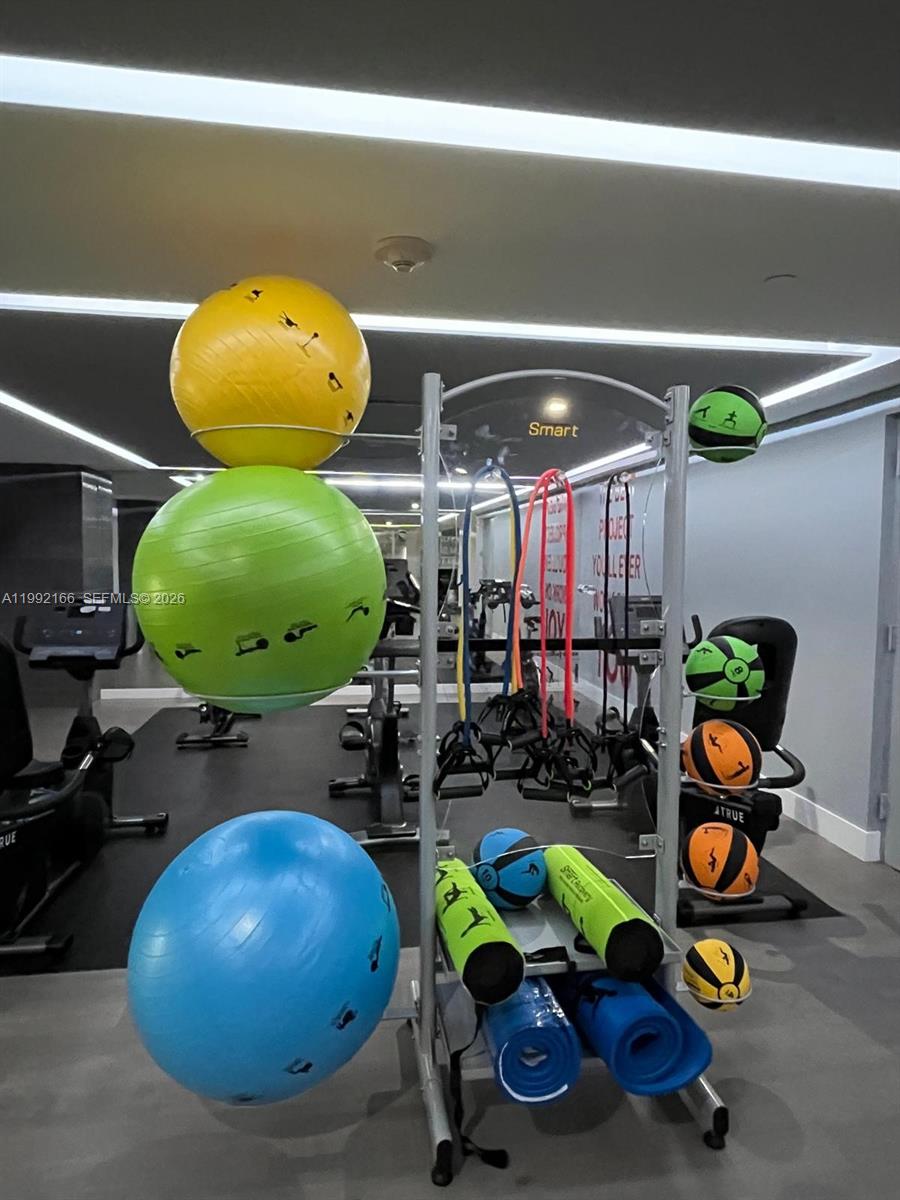 901 Brickell Key Boulevard, Unit 1609 Miami, FL 33131 - Photo 34 of 35 a room with gym equipment and wooden floor
