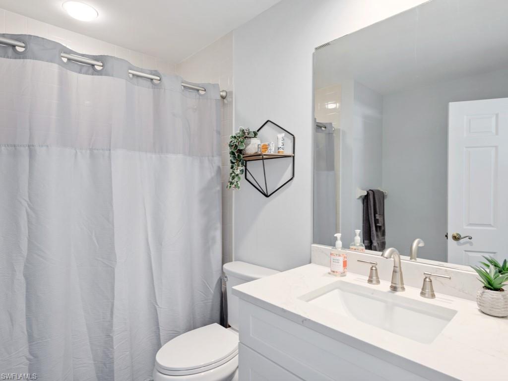 709 Augusta Boulevard, Unit 7095 Naples, FL 34113 - Photo 10 of 16 a bathroom with a sink vanity mirror and toilet