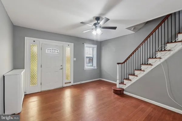 a view of an empty room with wooden floor and fan