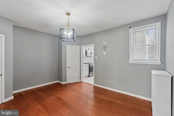 an empty room with wooden floor cabinet and windows