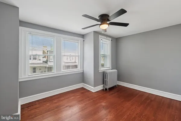 a view of empty room with wooden floor and fan