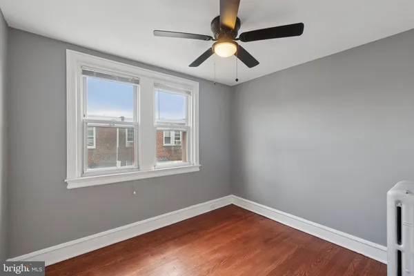 an empty room with wooden floor fan and windows