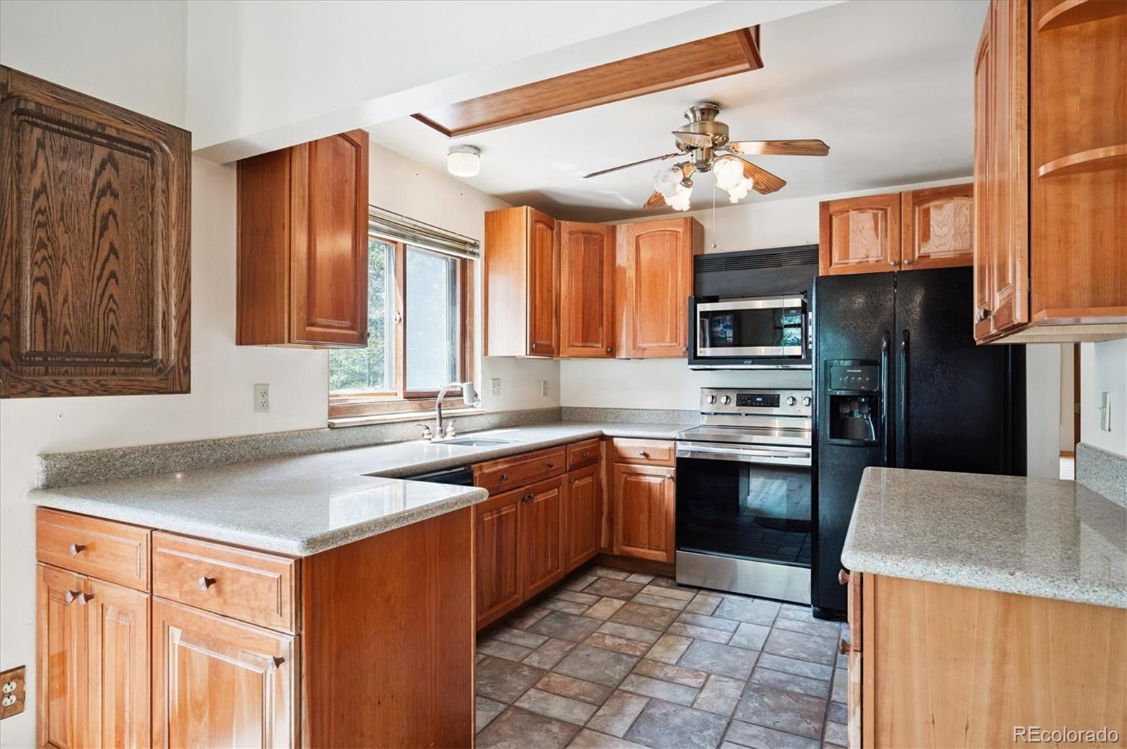 33623 Freda Road Pine, CO 80470 - Photo 5 of 27 a kitchen with stainless steel appliances granite countertop a sink dishwasher stove and refrigerator with wooden cabinets