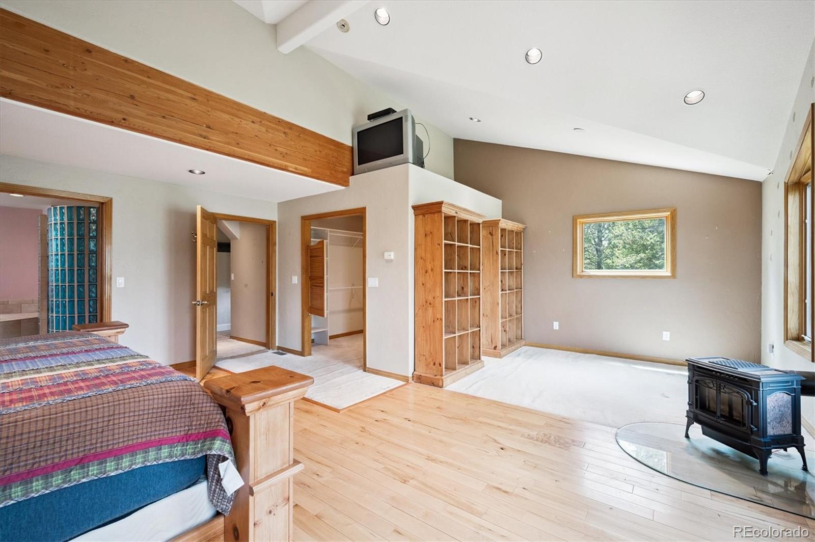 33623 Freda Road Pine, CO 80470 - Photo 10 of 27 a spacious bedroom with a large bed a chandelier and closet